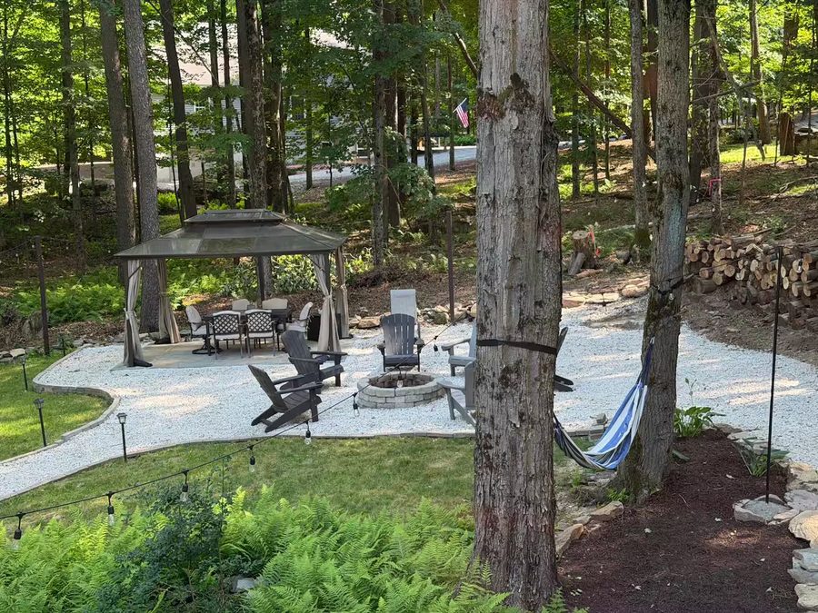 Firepit ringed with Adirondack chairs on the gravel patio among the pines